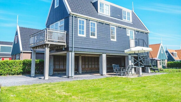 A two-story house with a balcony, a covered porch, and a staircase leading to the upper floor. - Holiday Home Built in Zaanse Style, Near Alkmaar (West-Graftdijk)