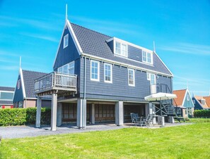 A two-story house with a balcony, a covered porch, and a staircase leading to the upper floor. - Holiday Home Built in Zaanse Style, Near Alkmaar (West-Graftdijk)