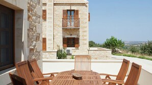 A stone building with a balcony, wooden chairs, and a table. - Dreamy Villa in Rethymnon With Private Pool (Rethymno)
