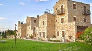 A row of stone buildings with balconies, a well-maintained lawn, and a clear sky. - Dreamy Villa in Rethymnon With Private Pool (Rethymno)