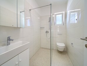 A modern bathroom with a glass shower enclosure, a white sink, and a toilet. - Villa in Cres With Sea Views & Pool (Cres)