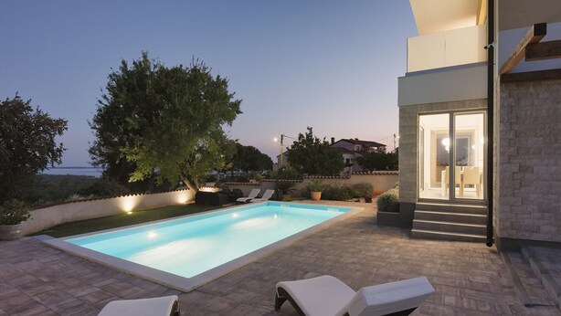 A swimming pool with lounge chairs, a tree, and a building with a staircase. - Villa in Peroj With Pool Near Barbariga Beach (Vodnjan)