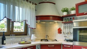 Une cuisine avec des meubles de couleur rouge, un four en acier inoxydable et une fenêtre donnant sur l’extérieur.