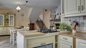 Une cuisine dotée d’un îlot central, de meubles blancs, d’une cuisinière et d’un coin repas avec des chaises et une table.