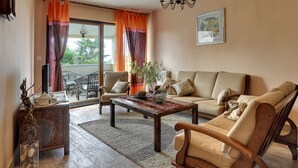 Un salon comprenant un canapé, des fauteuils, une table basse et un lustre.