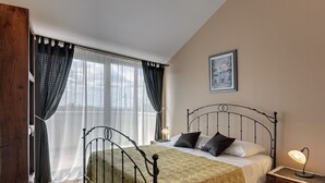 Une chambre à coucher avec un lit, une table de chevet, une lampe et une fenêtre avec des rideaux.