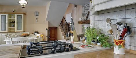 Une cuisine équipée d’une cuisinière à gaz, d’un plan de travail en bois et de divers ustensiles de cuisine.