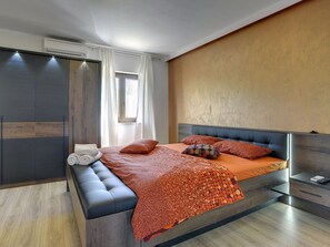 A modern bedroom with a bed, bench, and built-in wardrobe. - Villa in Rovinj With Private Pool and Sea Nearby (Rovinj)