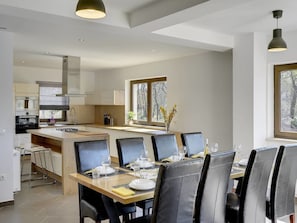 A modern kitchen with a central island, dining area with chairs, and a view of the outdoors through large windows. - Villa in Rovinj With Private Pool and Sea Nearby (Rovinj)