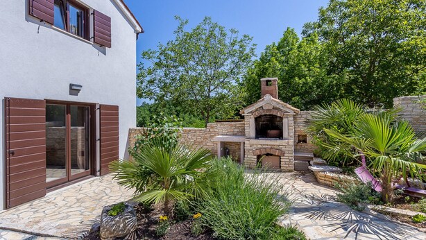 A modern house with a stone patio, a brick oven, and lush greenery. - Villa in Istria With Pool Near Croatian Sea (Svetvincenat)