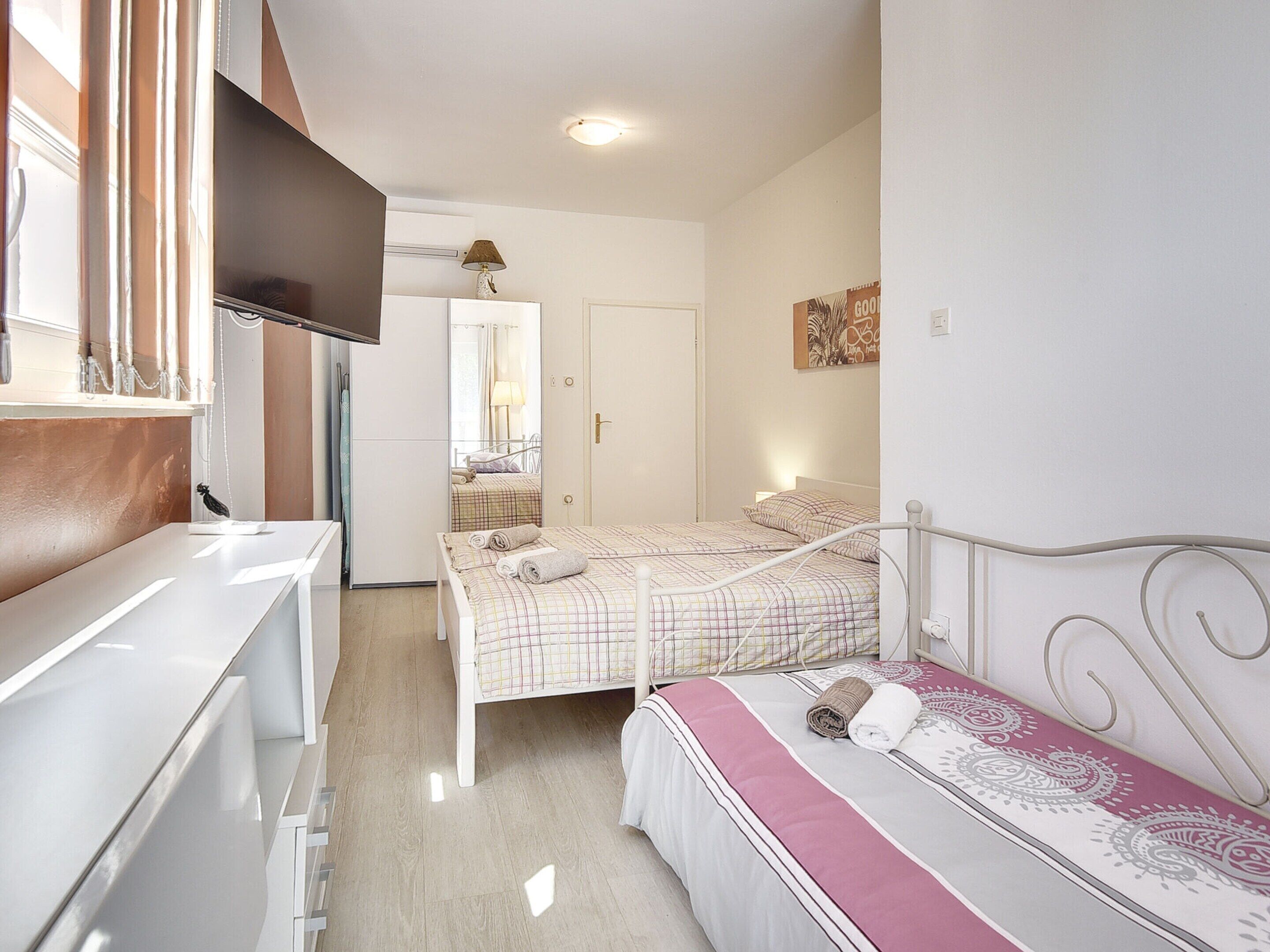 Une chambre avec deux lits, un bureau et un miroir.