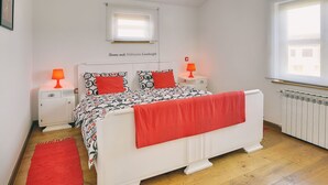 Ein Schlafzimmer mit einem Bett, zwei Nachttischen, einem Fenster und einer Heizung.