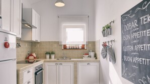 Eine moderne Küche mit weißen Schränken, einem Backofen, einer Spüle und einer Tafelwand mit Schrift.