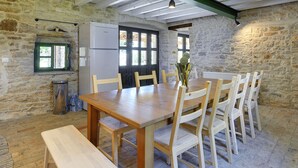 A rustic dining area with a wooden table and chairs, a refrigerator, and a window with a view. - Spacious Holiday Home in Svetvincenat With Pool (Svetvincenat)