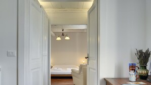 A hotel room with a wooden floor, a bed with white linens, a nightstand with a lamp, and a wooden table with a vase and books. - Spacious Holiday Home in Svetvincenat With Pool (Svetvincenat)