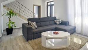 A modern living room with a grey sectional sofa, a round white coffee table, and a large potted plant. - Holiday Home in Liznjan Near the Beach (Liznjan)
