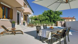 A sunlit outdoor patio with a pool table, lounge chairs, and a large umbrella. - Holiday Home in Liznjan Near the Beach (Liznjan)