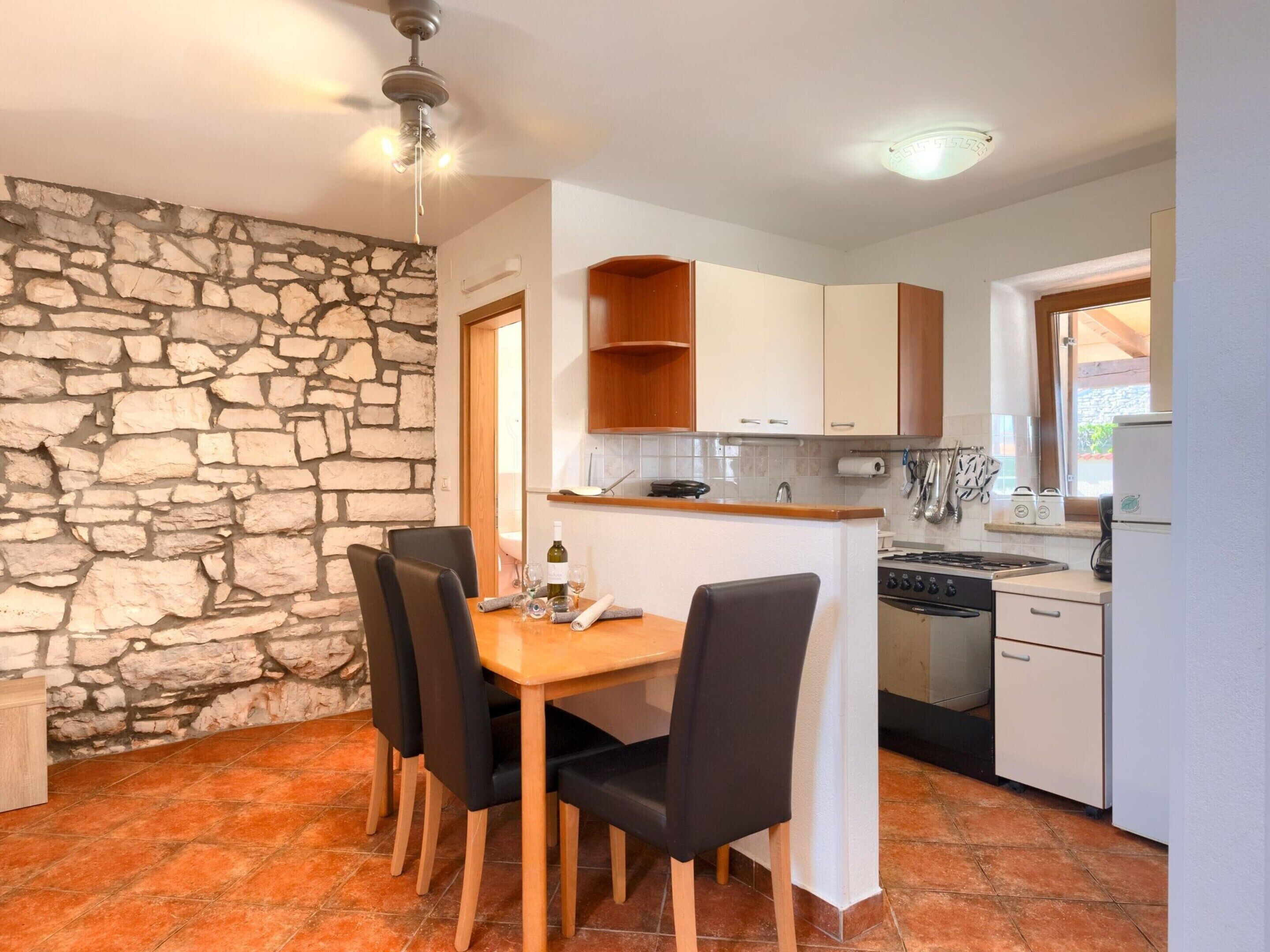 A compact kitchen with a stone wall, wooden dining table, and chairs.