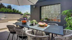 Une terrasse extérieure avec une table à manger, des chaises et des parasols.