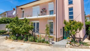 A two-story building with a balcony on the upper floor, a satellite dish on the left, and a green door on the right. - Apartment in Medulin Near the Sea (Medulin)