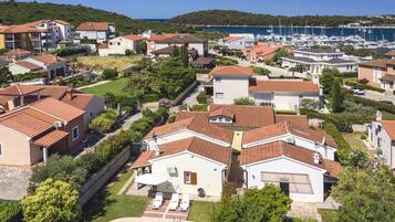 Stunning coastal homes with pools and lush gardens, surrounded by a marina and scenic hills.
