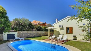 Una piscina con lettini e un muro in pietra.