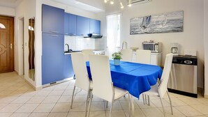 Una cucina moderna con armadietti blu, una zona pranzo con tovaglia blu e un quadro raffigurante una barca a vela.