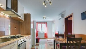 Une cuisine moderne équipée d’une cuisinière à gaz, d’un four et d’un évier. On y trouve également un coin repas avec une table et des chaises.
