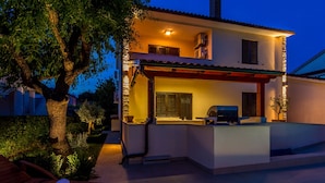 Et moderne hus med to etager, en pool, udendørs siddepladser og en veloplyst terrasse.