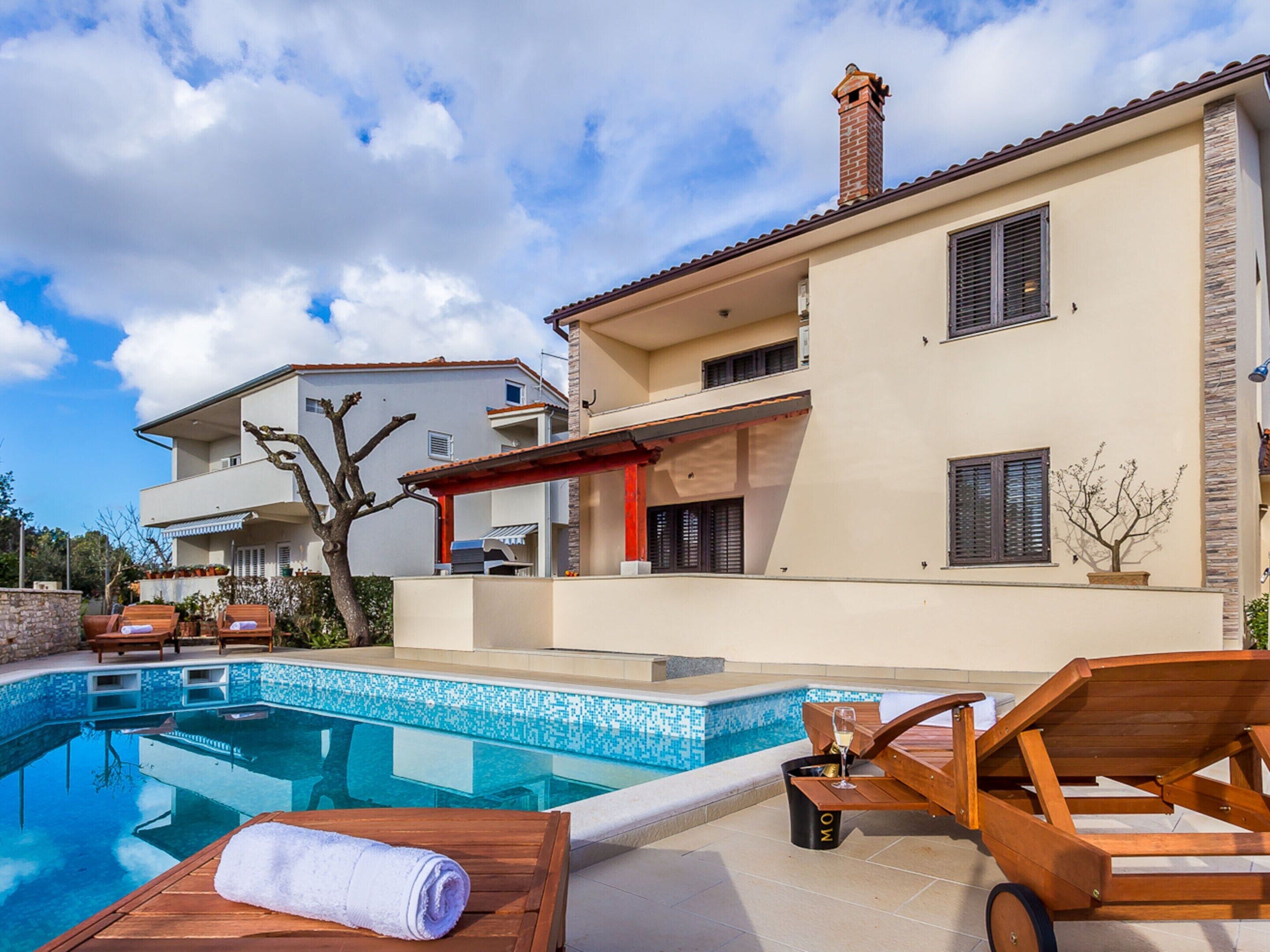 A modern house with a swimming pool, outdoor furniture, and a clear sky.