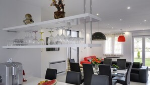 A modern kitchen with white cabinetry, a dining area with black chairs, and a red sofa in the living room. - Villa in Bratulici With Pool Near Beach (Marcana)