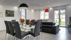 A modern living room with a glass dining table, black chairs, a black sofa, and a red pendant light. - Villa in Bratulici With Pool Near Beach (Marcana)