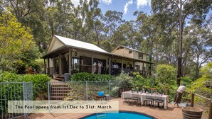 A pool area with a wooden deck, a pool, and a building with a porch. - The Getaway Perth Hills (Roleystone)