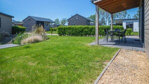 Ett bostadsområde med hus, en inglasad uteplats och en välskött gräsmatta.
