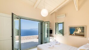 A bedroom with a bed, a painting, and a view of the sea. - Luxurious Villa in Vasiliki with Swimming Pool & Hot Tub (Lefkada)