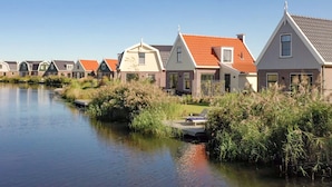 A row of houses with red roofs by a calm water body. - Spacious Holiday Home on Markermeer near Amsterdam (Uitdam)