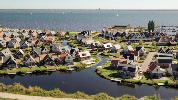 A residential area with houses along a canal, boats in the water, and a distant view of a city skyline. - Spacious Holiday Home on Markermeer near Amsterdam (Uitdam)
