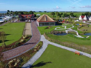 A large building with a glass facade, surrounded by a well-maintained lawn and a winding path.