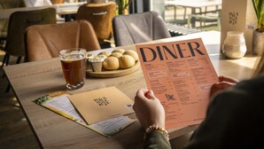 A person holding a menu at a restaurant table with a drink and bread rolls. - Modern Lodge With Dishwasher, Near Helmond (Mierlo)
