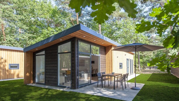 A modern house with a patio area, large windows, and a dining table with chairs. - Modern Lodge With Dishwasher, Near Helmond (Mierlo)