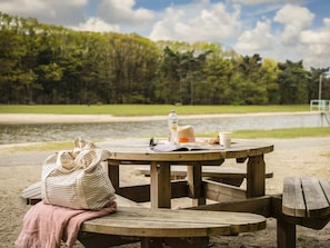 A picnic table with a bag, a bottle, and a sandwich on it.