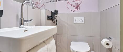A bathroom with a white sink, a toilet, and a towel hanging on the wall.