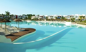 Une piscine d’hôtel avec des chaises longues et des parasols, entourée de bâtiments blancs.