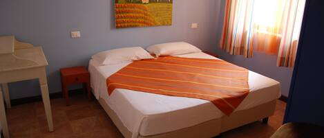 A bedroom with a bed, a desk, and a painting on the wall.