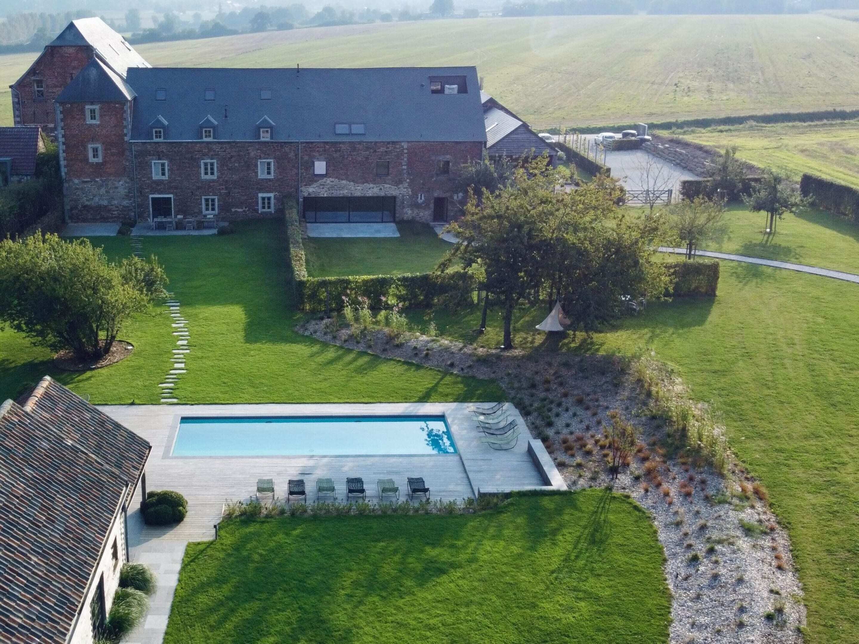 A large estate with a swimming pool, a well-maintained lawn, and a brick building with multiple windows.