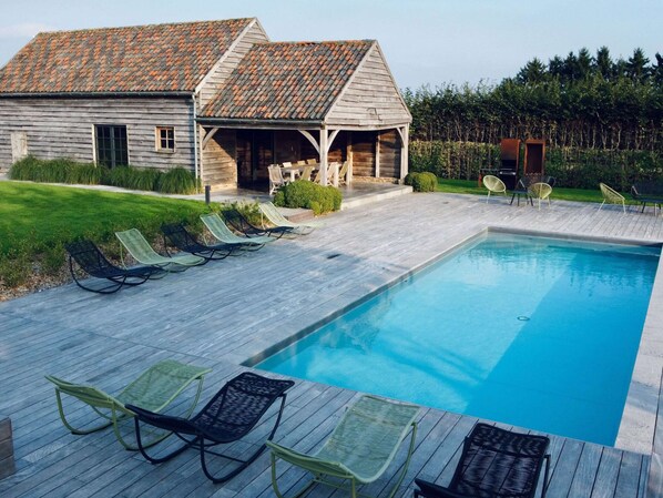 A swimming pool with lounge chairs and a wooden deck.