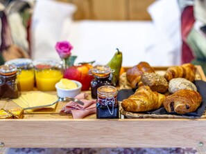 A breakfast tray with pastries, fruits, jams, and a small bowl of butter.