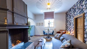 A living room with a fireplace, a sofa, a coffee table, and a dining area with chairs and a table. - Splendid Castle in Perwez-haillot With Sun-loungers (Ohey)