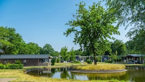 A lakeside hotel with multiple cabins, a central pond, and lush greenery.