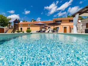 A clear swimming pool with lounge chairs and umbrellas, surrounded by buildings with a Mediterranean architectural style. - Charming Villa With Private Swimming Pool (Zminj)